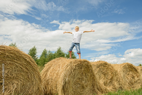 Teenager jumps on hay. Happy boy.