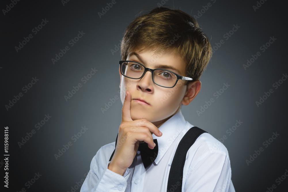 doubt, expression and people concept - boy thinking over gray background doubt, expression and people concept - boy thinking over gray background