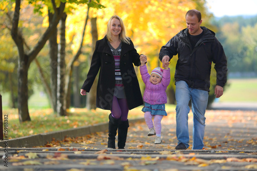 The young happy family spends time on walk in autumn park
