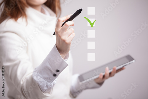 Young business woman checking on checklist box. Gray background.