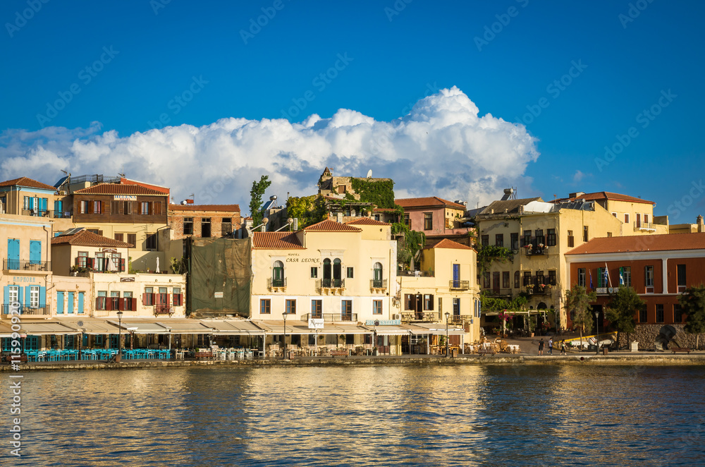 View of the old venetian port of Chania on Crete island, Greece. Tourists relaxing on promenade.