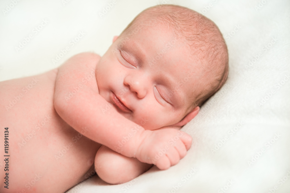 Smiling newborn baby sleeping on white blanket Smiling newborn baby sleeping on white blanket