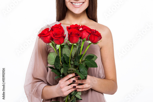 Beautiful tenderness. Beautiful young woman in pretty dress holding bouquet of flowers while standing against white background