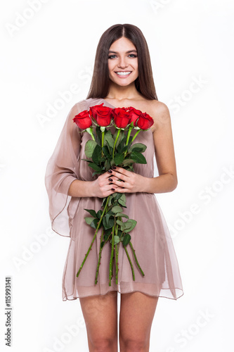 Fototapeta Naklejka Na Ścianę i Meble -  The most beautiful flowers for the most beautiful girl. Beautiful young woman in pretty dress holding bouquet of flowers while standing against white background
