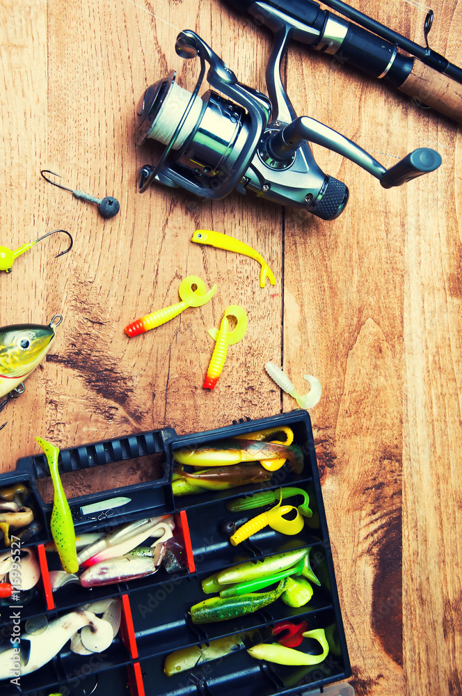 Fishing baits and rod isolated on wooden background