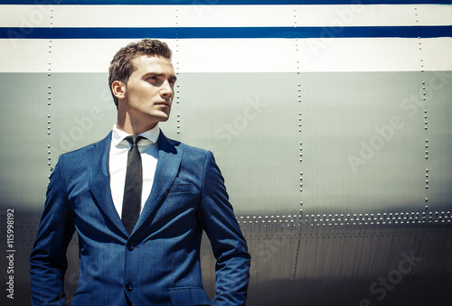Handsome young man with short hair wearing classic blue suit and photo