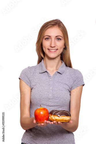 Choose, healthy food or not. Attractive young woman hold donut and apple over white background.