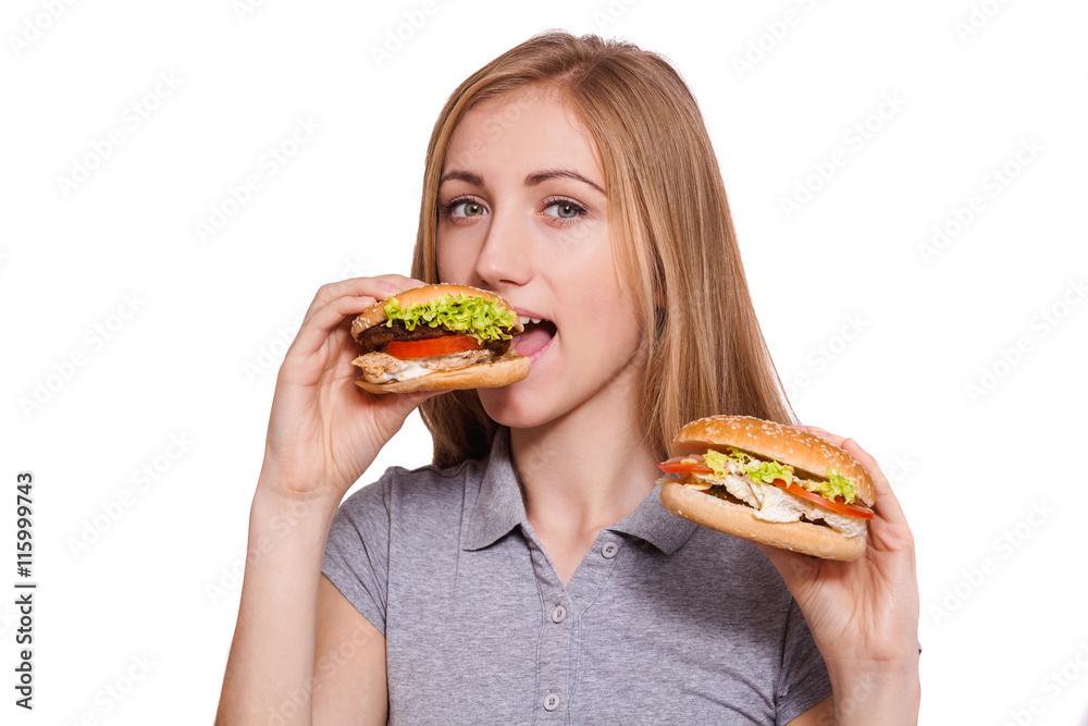 Quick snack. Beautiful young woman eat burger and hold another one over white background. Quick snack. Beautiful young woman eat burger and hold another one over white background.