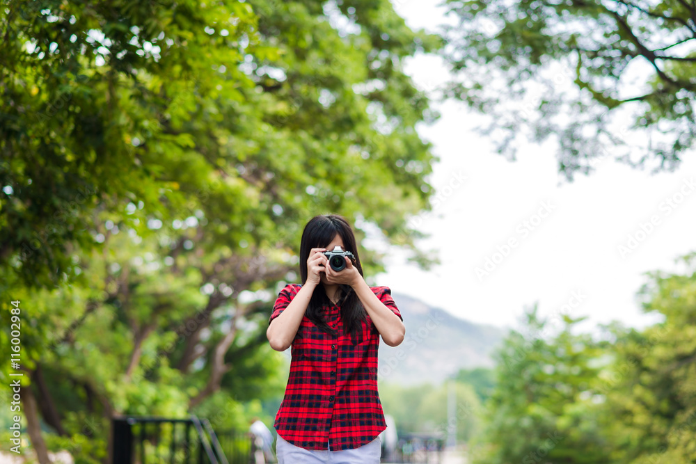 Asian female photographer with mirrorless camera on railway