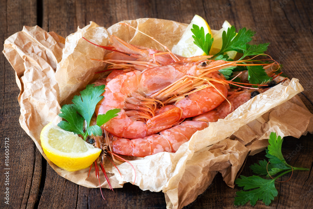 Uncooked prawns with slices of lemon and parsley on dark rustic wooden background Uncooked prawns with slices of lemon and parsley on dark rustic wooden background
