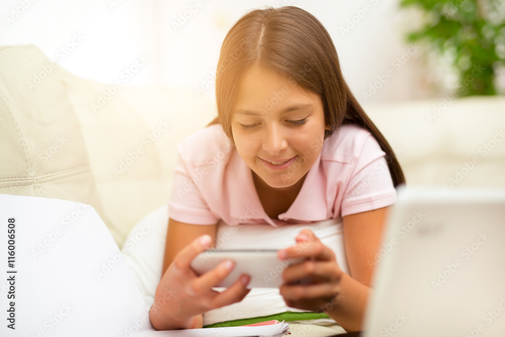 Happy girl using a mobile phone lying on the bed at home Happy girl using a mobile phone lying on the bed at home