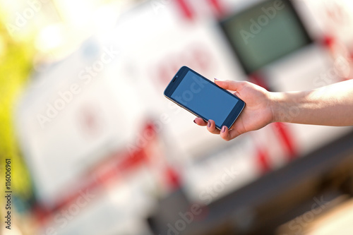 People hand with smartphone calling at emergency car background