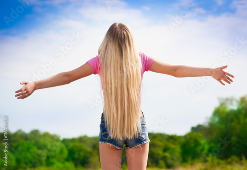Girl in nature, pink t-shirt, blue shorts, half height, back
