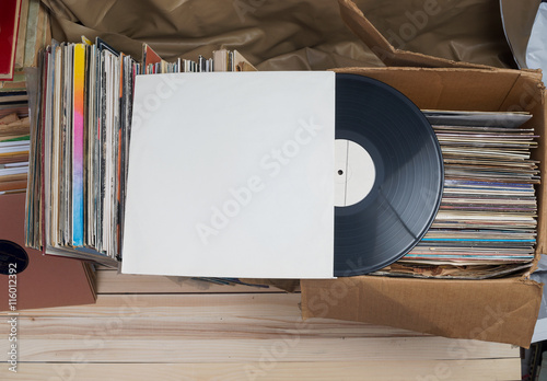 Retro styled image of a collection of old vinyl record lp's with sleeves on a wooden background. Top view.  Copy space