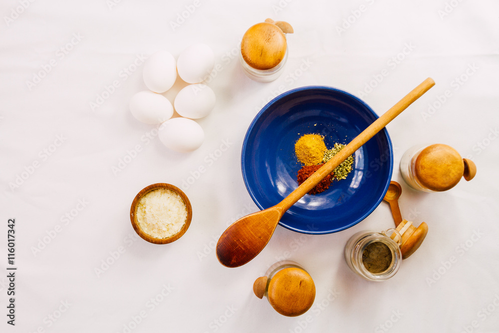 Blue bowl with spices, spices racks, wooden spoon, eggs and dehy Blue bowl with spices, spices racks, wooden spoon, eggs and dehy