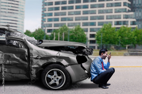 Man with broken car speaks on mobile phone © Creativa Images