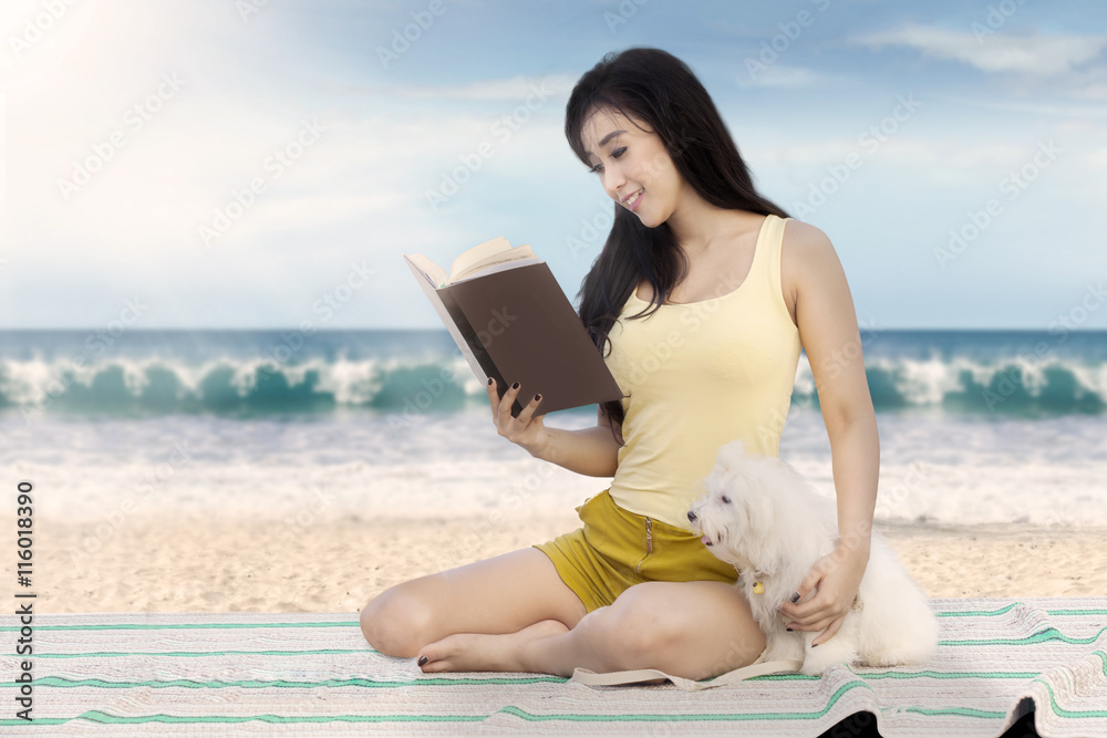Fototapeta premium Pretty model with dog reads book at shore
