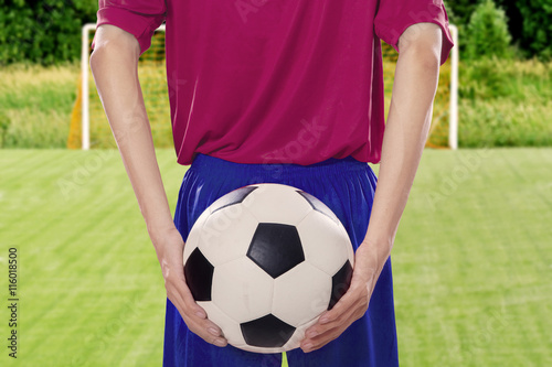 Soccer player holds ball at behind © Creativa Images