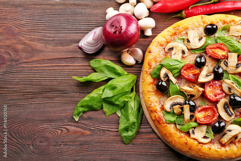 Delicious tasty pizza with ingredients on wooden table Delicious tasty pizza with ingredients on wooden table