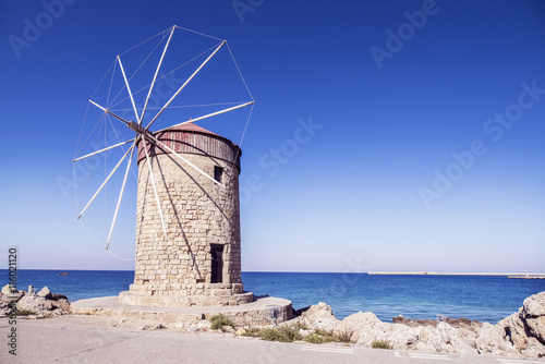 The tower with the windmill on the sea background