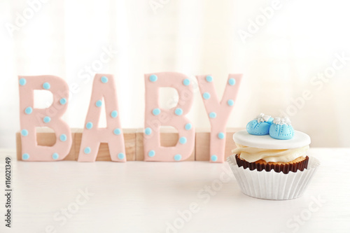 Word "Baby" with cupcake on light background