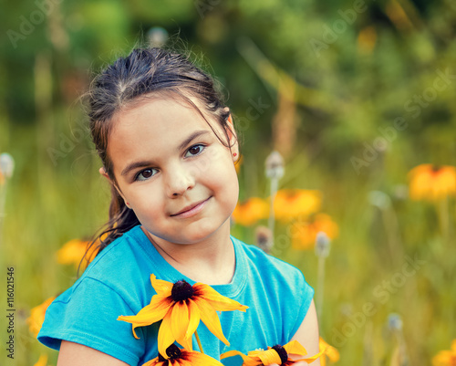 portrait of smiling little girl walking on the flower meadow photo