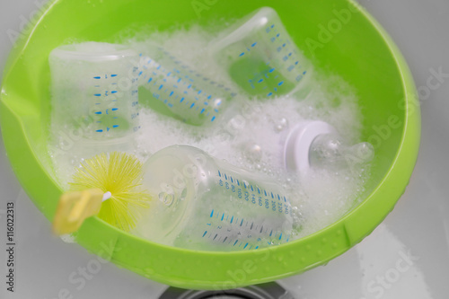 Sterilizing baby bottles in plastic green basin