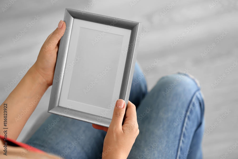 Female hands holding photo frame on light background