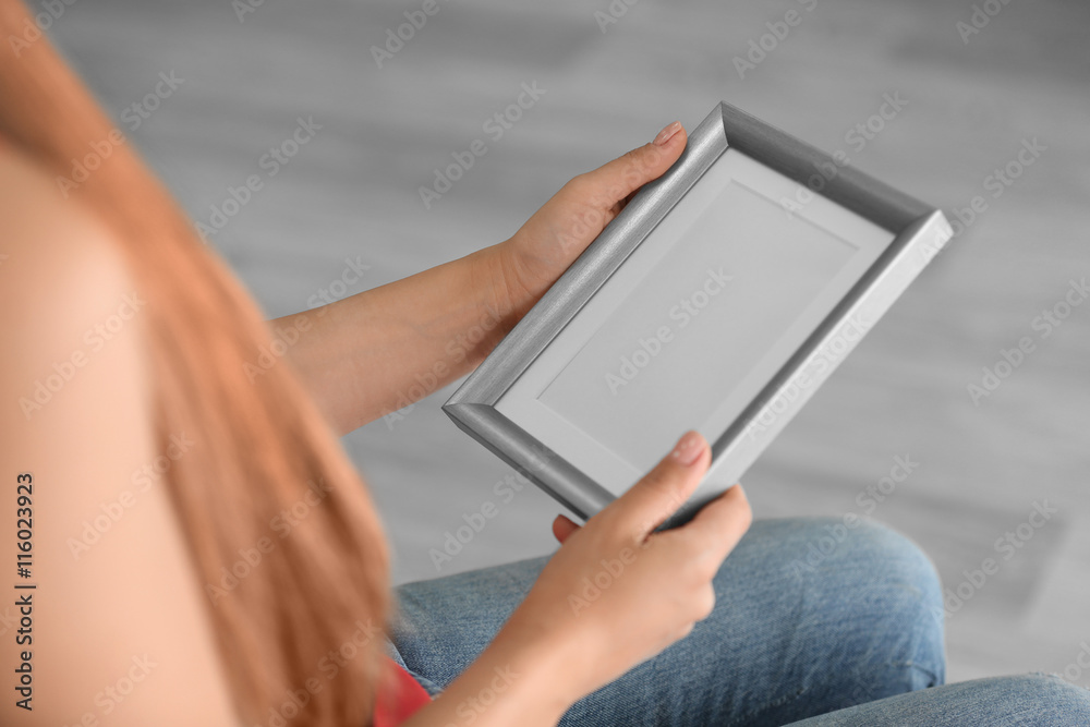 Female hands holding photo frame on light background