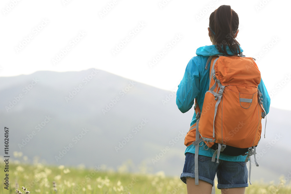 young woman hiker walking on trail in grassland