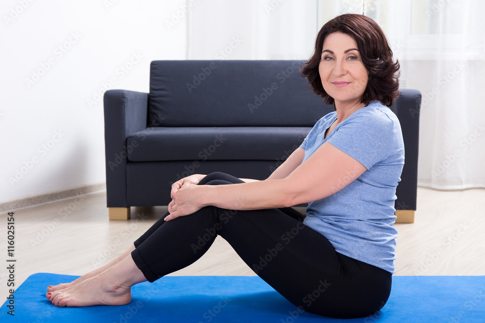 slim sporty mature woman doing exercises on yoga mat at home Stock Photo