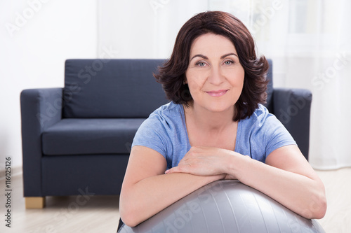 portrait of sporty mature woman with fitness ball at home