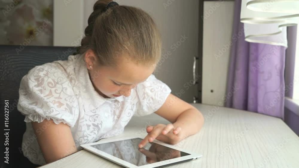 Cute little girl uses a digital tablet computer Cute little girl uses a digital tablet computer