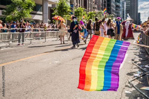 Rainbow flag floating in front of blurred Toronto gay pride participants photo
