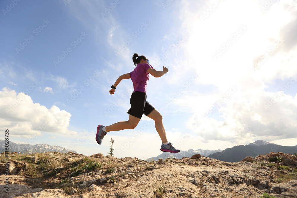 healthy young woman trail runner running on beautiful mountain peak