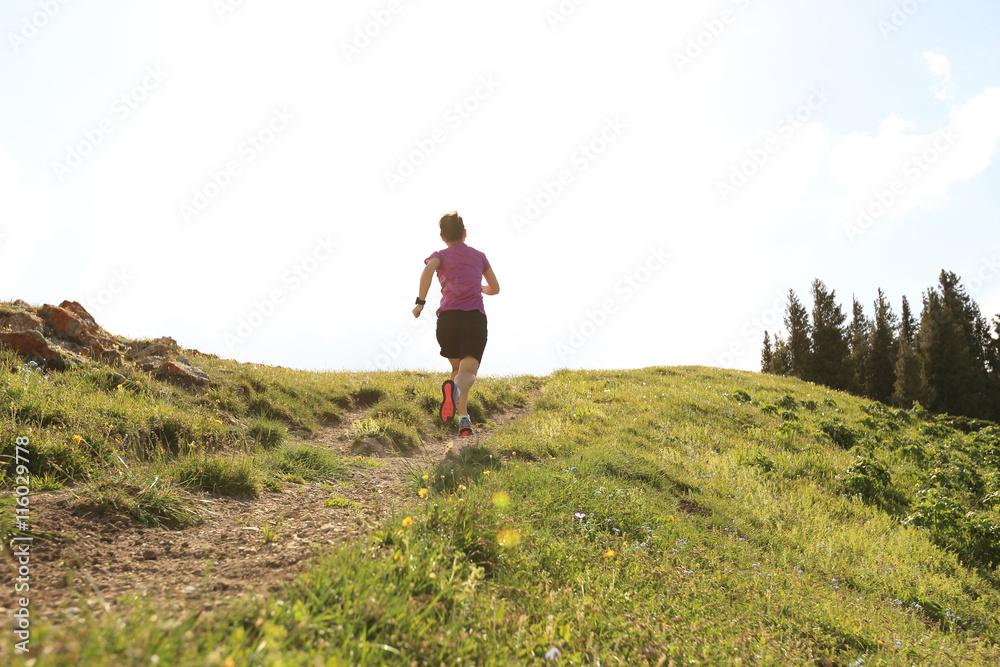 healthy young woman trail runner running on beautiful mountain peak