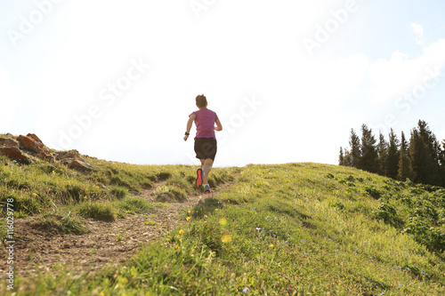 healthy young woman trail runner running on beautiful mountain peak