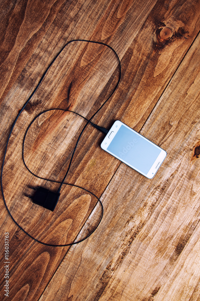 top view of white smartphone and adapter charger