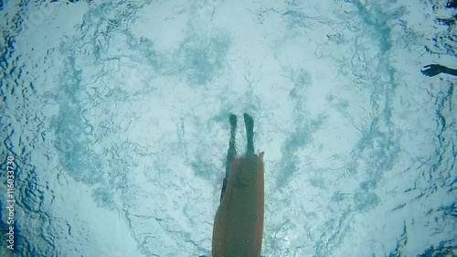 A slow motion underneath view of a boy jumping into a pool on a raft.  	