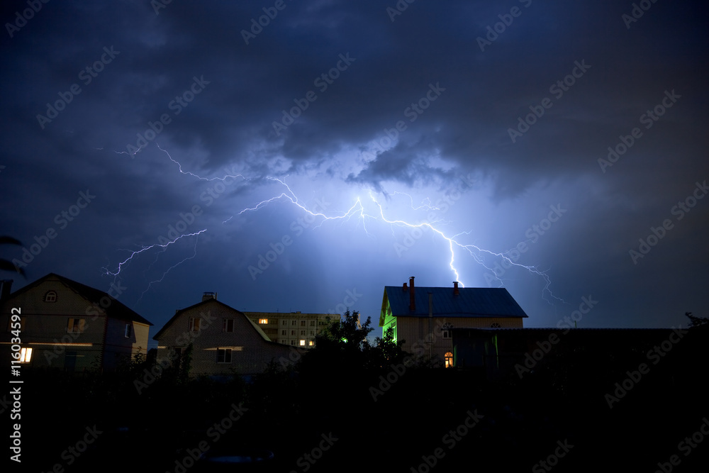 Lightning in the cloudy sky over village