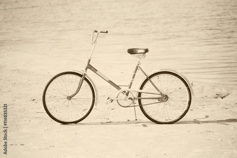 Fototapeta premium Ancient bicycle on beach - retro sepia