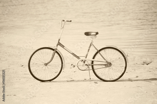 Ancient bicycle on beach - retro sepia