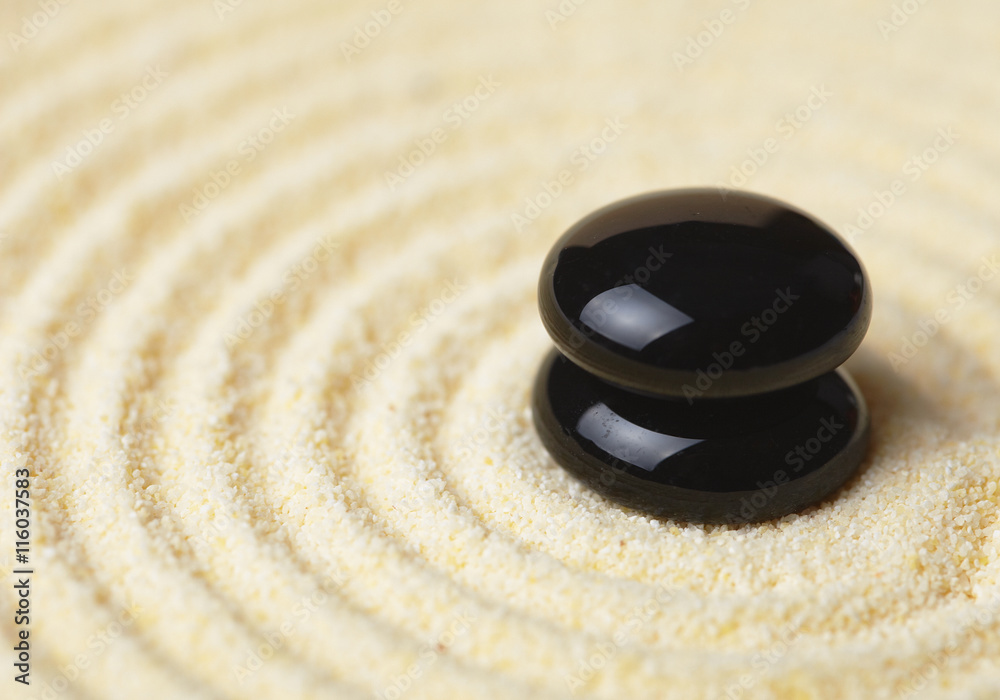 Naklejka premium Two black stones put in a pile on sand