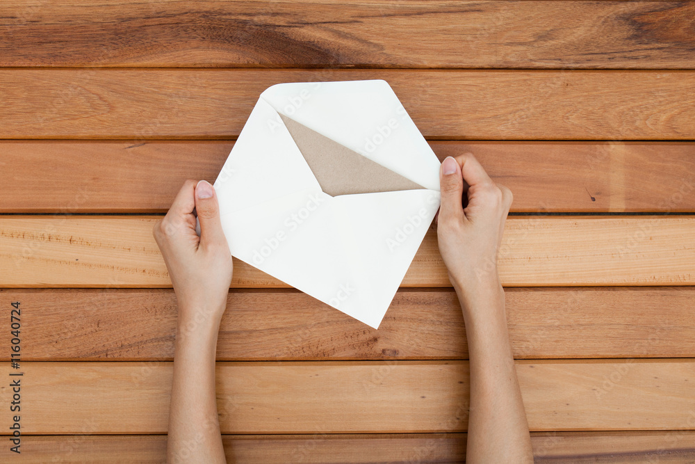 woman hand hold a envelope and post card on the wood desk, top v
