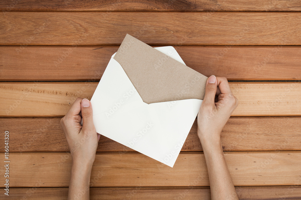 woman hand hold a envelope and post card on the wood desk, top v woman hand hold a envelope and post card on the wood desk, top v