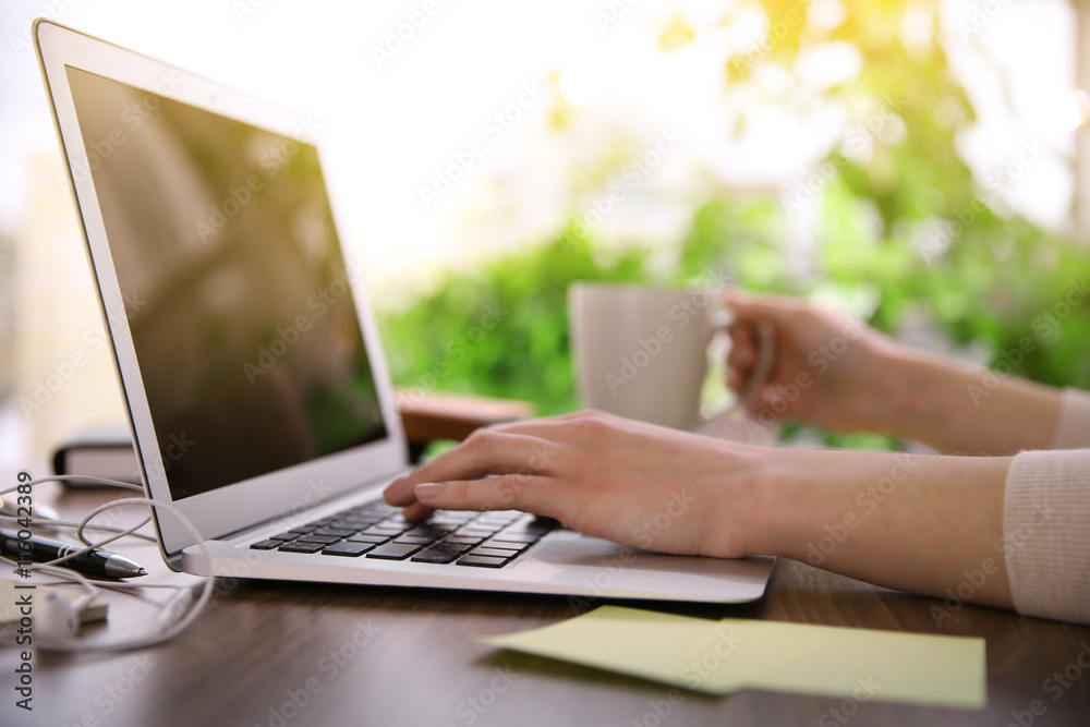 Female hands working with a laptop outdoor on blurred green plant background Female hands working with a laptop outdoor on blurred green plant background
