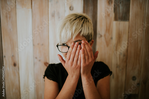 Young girl in glasses covering face with hands photo