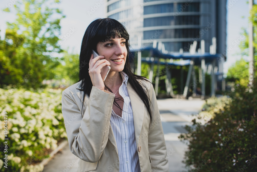 Smiling black-haired woman talking over cell Smiling black-haired woman talking over cell