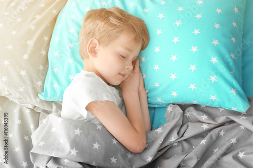 Adorable little boy sleeping in bed