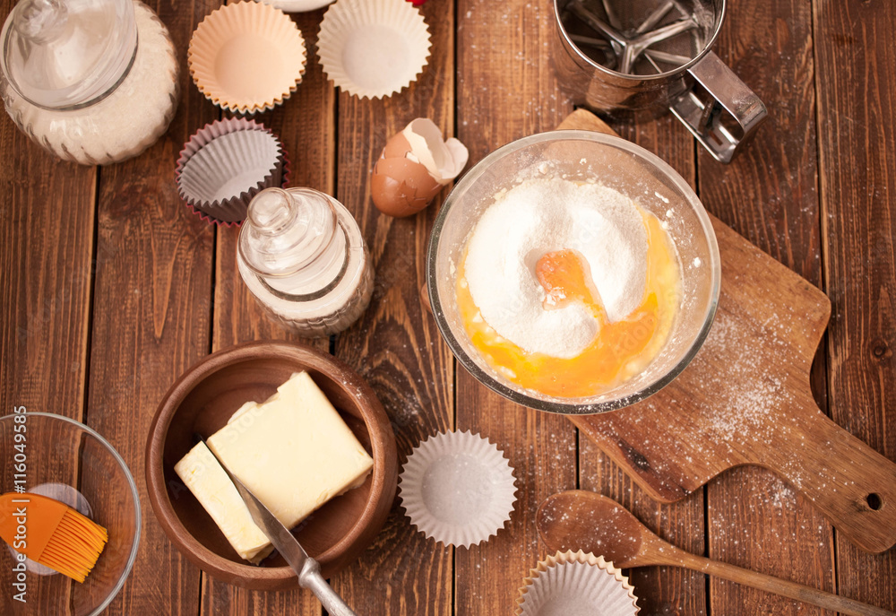 tools and ingredients for making cupcakes on a wooden background. Food texture. Flour, eggs, oil, mix for pastries. Top view tools and ingredients for making cupcakes on a wooden background. Food texture. Flour, eggs, oil, mix for pastries. Top view